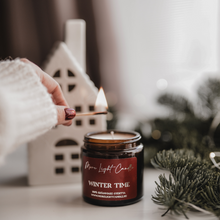 Kép betöltése a galériamegjelenítőbe: Kézzel öntött Winter Time gyertya ezüst tetővel, mellette friss körte és vörösáfonya, havas dekorációban.