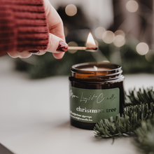 Kép betöltése a galériamegjelenítőbe: Christmas Tree szójagyertya fa tálcán, fenyőágakkal és tobozokkal körülvéve, ünnepi háttérrel.