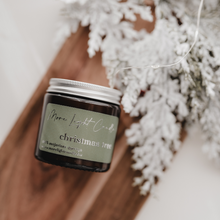 Kép betöltése a galériamegjelenítőbe: Christmas Tree szójagyertya fa tálcán, fenyőágakkal és tobozokkal körülvéve, ünnepi háttérrel.