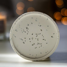 Kép betöltése a galériamegjelenítőbe: Világos jesmonite ásványgyanta alátét apró fekete terrazzo szemcsékkel – elegáns gyertyatartó tálka a More Light Candle választékából.