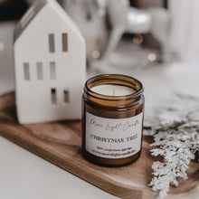 Kép betöltése a galériamegjelenítőbe: Christmas Tree szójagyertya fa tálcán, fenyőágakkal és tobozokkal körülvéve, ünnepi háttérrel.