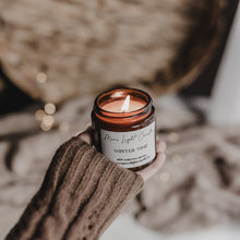 Kép betöltése a galériamegjelenítőbe: Kézzel öntött Winter Time gyertya ezüst tetővel, mellette friss körte és vörösáfonya, havas dekorációban.