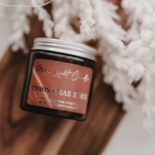 Kép betöltése a galériamegjelenítőbe: Meghitt karácsonyi hangulatú fotó a Christmas Spice szójagyertyáról, természetes díszítéssel és gyertyafénnyel.