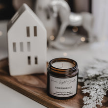 Kép betöltése a galériamegjelenítőbe: Gingerbread szójagyertya fa tálcán, mézeskalács figurákkal és fahéjrúddal körülvéve.