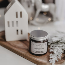 Kép betöltése a galériamegjelenítőbe: Kézzel öntött Winter Time gyertya ezüst tetővel, mellette friss körte és vörösáfonya, havas dekorációban.