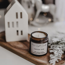 Kép betöltése a galériamegjelenítőbe: Kézzel öntött Winter Time gyertya ezüst tetővel, mellette friss körte és vörösáfonya, havas dekorációban.