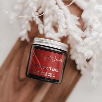 Kézzel öntött Winter Time gyertya ezüst tetővel, mellette friss körte és vörösáfonya, havas dekorációban.