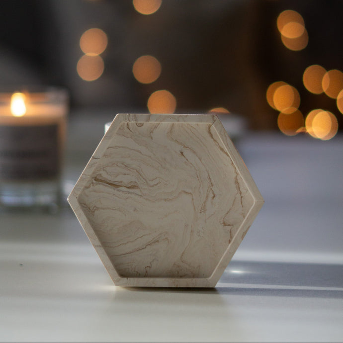 Hatszögletű bézs márványmintás jesmonite ásványgyanta alátét – stílusos és modern gyertyatartó tálka a More Light Candle kollekcióból.