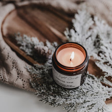 Kép betöltése a galériamegjelenítőbe: Kézzel öntött Winter Time gyertya ezüst tetővel, mellette friss körte és vörösáfonya, havas dekorációban.
